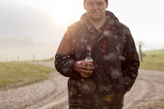 Young man having a beer in the rain