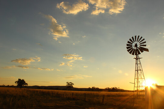 Windmill silhouette on a farm at sunset