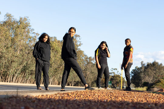 four teenagers dressed in black standing on the edge of a road