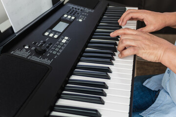 Fototapeta na wymiar Close-up of hands playing a piano keyboard looking at sheet music