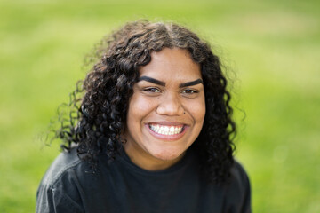 smiling young woman wearing black against green grass background