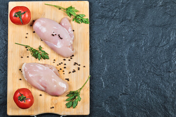 Raw chicken fillets on wooden board with fresh vegetables