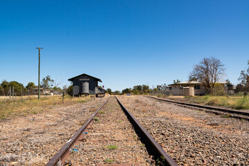 Low view along railway lines to a country station with a blue sky