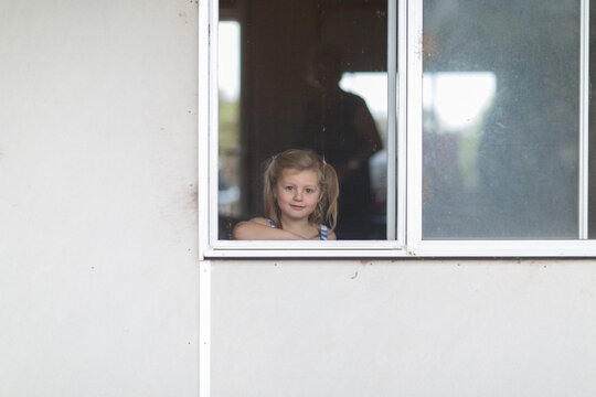 Child looking out window through flyscreen
