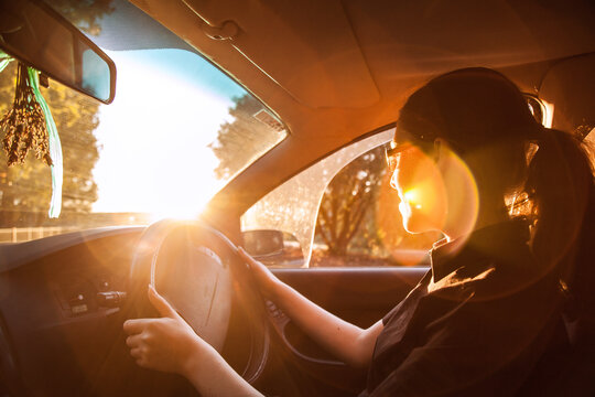 Teen girl driving car with lens flare