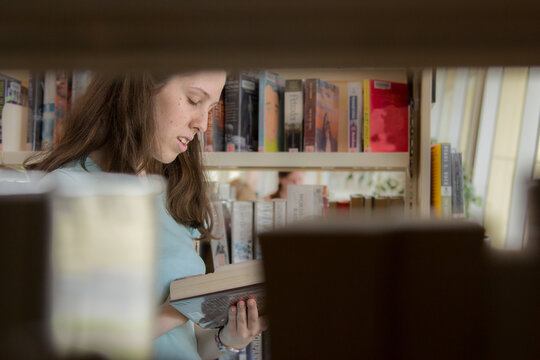 Young lady choosing a book to read from the local library