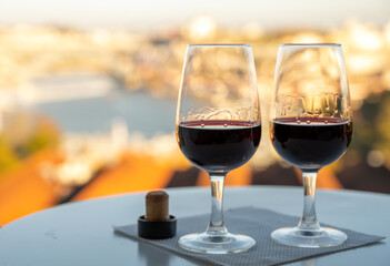 Tasting of different fortified dessert ruby, tawny port wines in glasses with view on Douro river, porto lodges of Vila Nova de Gaia and city of Porto, Portugal