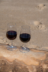 Tasting of different fortified dessert ruby, tawny port wines in glasses on sandy beach with view on waves of Atlantic ocean near Vila Nova de Gaia and city of Porto, Portugal
