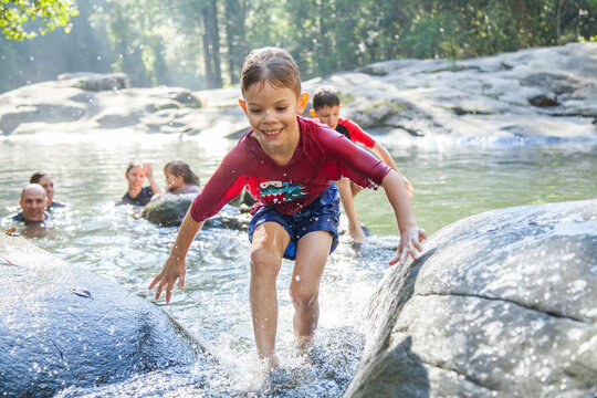 Seven year old boy splashing in river water between two rocks