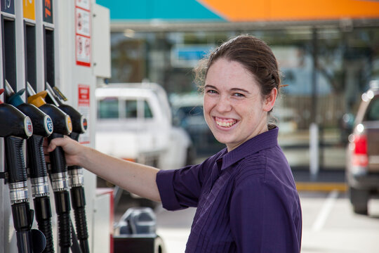 Teen girl filling her car up with petrol at the service station
