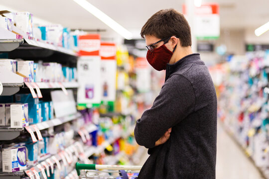 Man with folded arms and face mask in shopping aisle, choosing what to buy