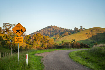 School bus turning sign on rural country road at sunset