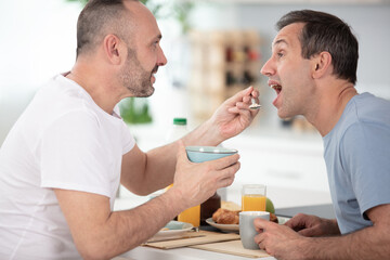 homosexual man feeding cereals to his partner