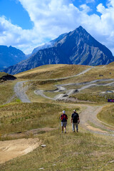 Old man and woman hiking in Ecrins alpine mountain range in summer, Les deux Alpes, France