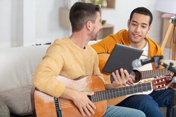 musician teaching his friend playing guitar