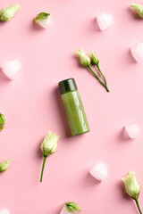 Obraz na płótnie Canvas Shower gel green clear cosmetic bottle, ice cubes, spring flowers on pink background. Natural beauty product. Flat lay, top view.