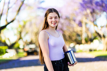 Happy young teen girl carrying books