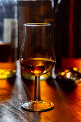 Dram of single malt scotch whisky and bottles on background