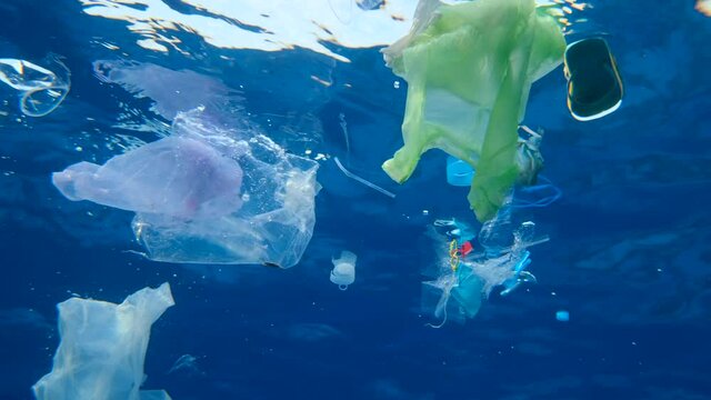 Slow motion, Massive plastic and other debris slowly drifts under surface of the blue ocean in the sun lights. Plastic garbage environmental pollution problem. Plastic pollution of the Red Sea