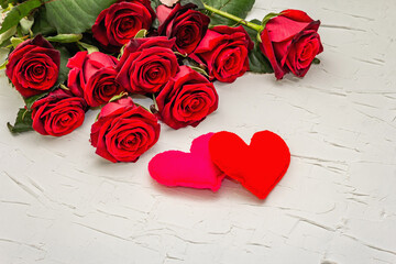 Fresh burgundy roses with felt hearts on a white putty background