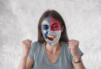 Young woman with painted flag of America state North Carolina looking energetic with fists up