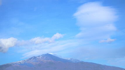 The mount Etna Volcano with smoke and clouds in winter. banner