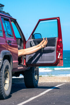 Woman rests legs in the car at a beach carpark