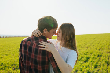 Loving couple smiling and hugging on the green grass at sunny spring day. Love story.