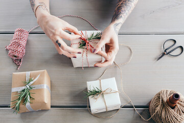 Female hands tying bows on stylishly wrapped Christmas gifts