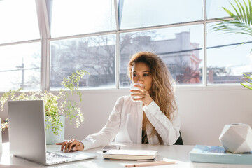 Female sipping water while working in a bright clinical white office