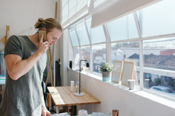 Man in his 20s on the phone in a creative studio office