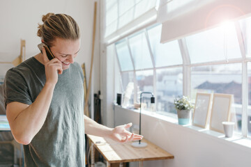 Young man questioning someone on the phone in an office