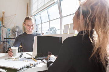 Coworkers at a shared desk in a creative studio workplace