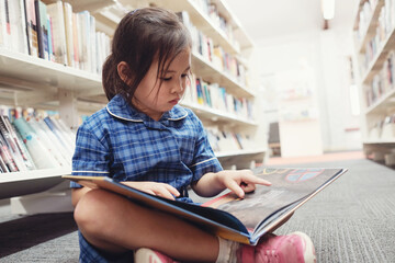 Young student girl reading in library
