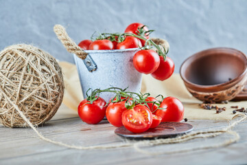 Bucket of tomatoes and half cut tomato on wooden table