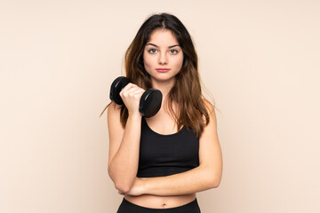 Young sport woman making weightlifting isolated on beige background keeping arms crossed