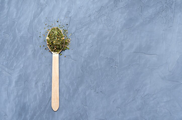 Dried herbs and spices in a wooden spoon on a gray concrete background. Provencal herbs, basil, rosemary, oregano, marjoram, thyme, sage, mint, thyme. space for text - obrazy, fototapety, plakaty