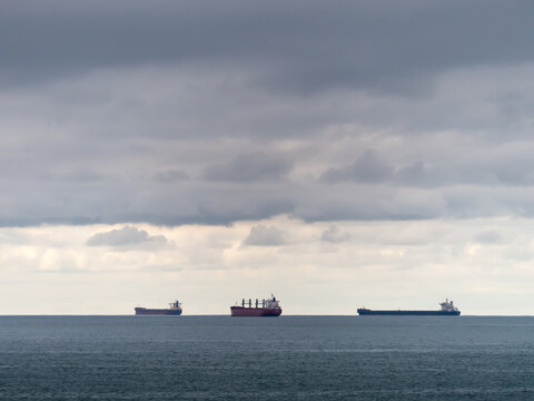 Three bulk carriers on the horizon on a cloudy day