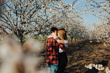 Couple in love hugging near blossoming trees in the garden. Passion and love concept.