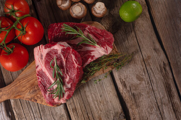 Fresh scythe of marbled beef steak with mushrooms lime and tomatoes on a wooden background with space for an inscription.Culinary and recipe book