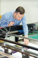 engineer leaning over printing machine