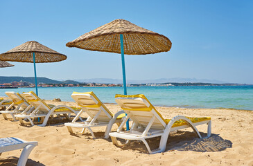 Empty sunbeds and parasols on morning, by the sea. Sand beach in luxury hotel resort near sea. Beautiful morning seascape.