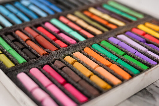 Multicolored artists soft pastels, chalks, crayons in the box. Spectrum of colors. Background. Selective focus.