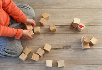 a child plays on the floor with wooden cubes. The view from the top