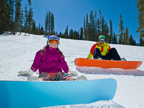 USA, Colorado, Telluride, Father and daughter (10-11) posing with snowboards in winter scenery