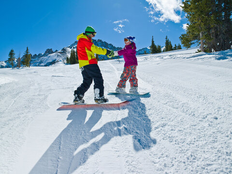 USA, Colorado, Telluride, Father and daughter (10-11) snowboarding