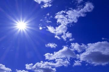 Blue sky with clouds, bright sun with rays and highlights.