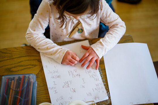 Above-view of a small child sitting at a table writing a story