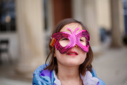 Close-up of small girl with bright eyes wearing a shiny butterfly mask