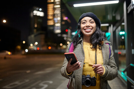 smiling woman standing using his cellphone in the street at night